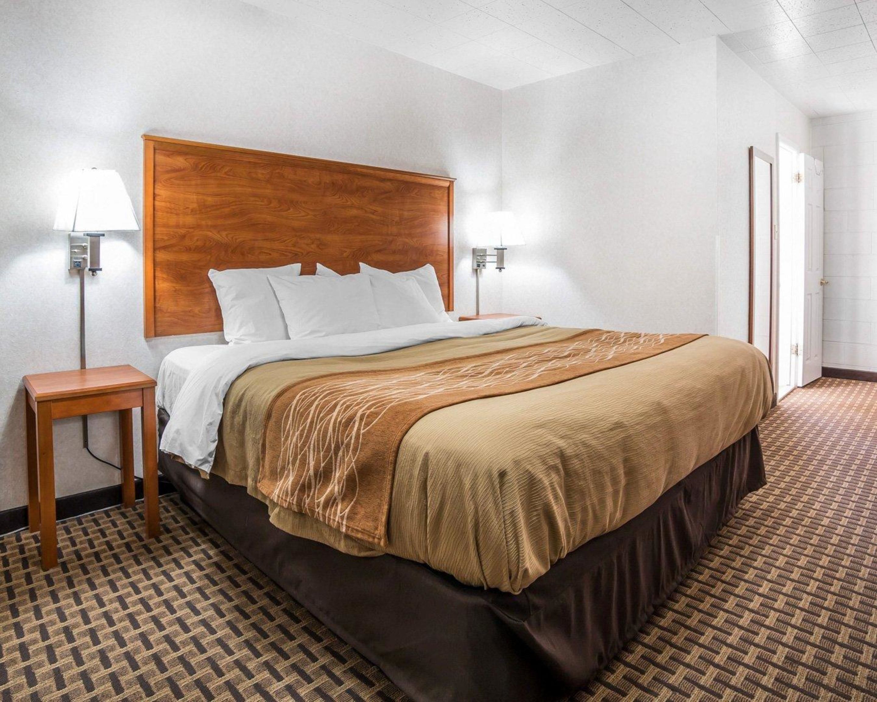 A hotel room with a large bed, two bedside tables, and a wooden headboard.