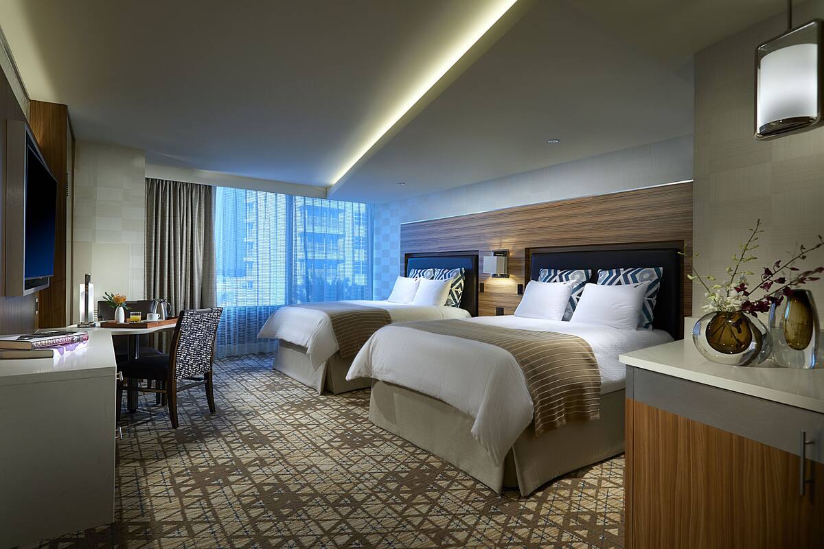 Une chambre d’hôtel avec deux lits, un bureau et une télévision.