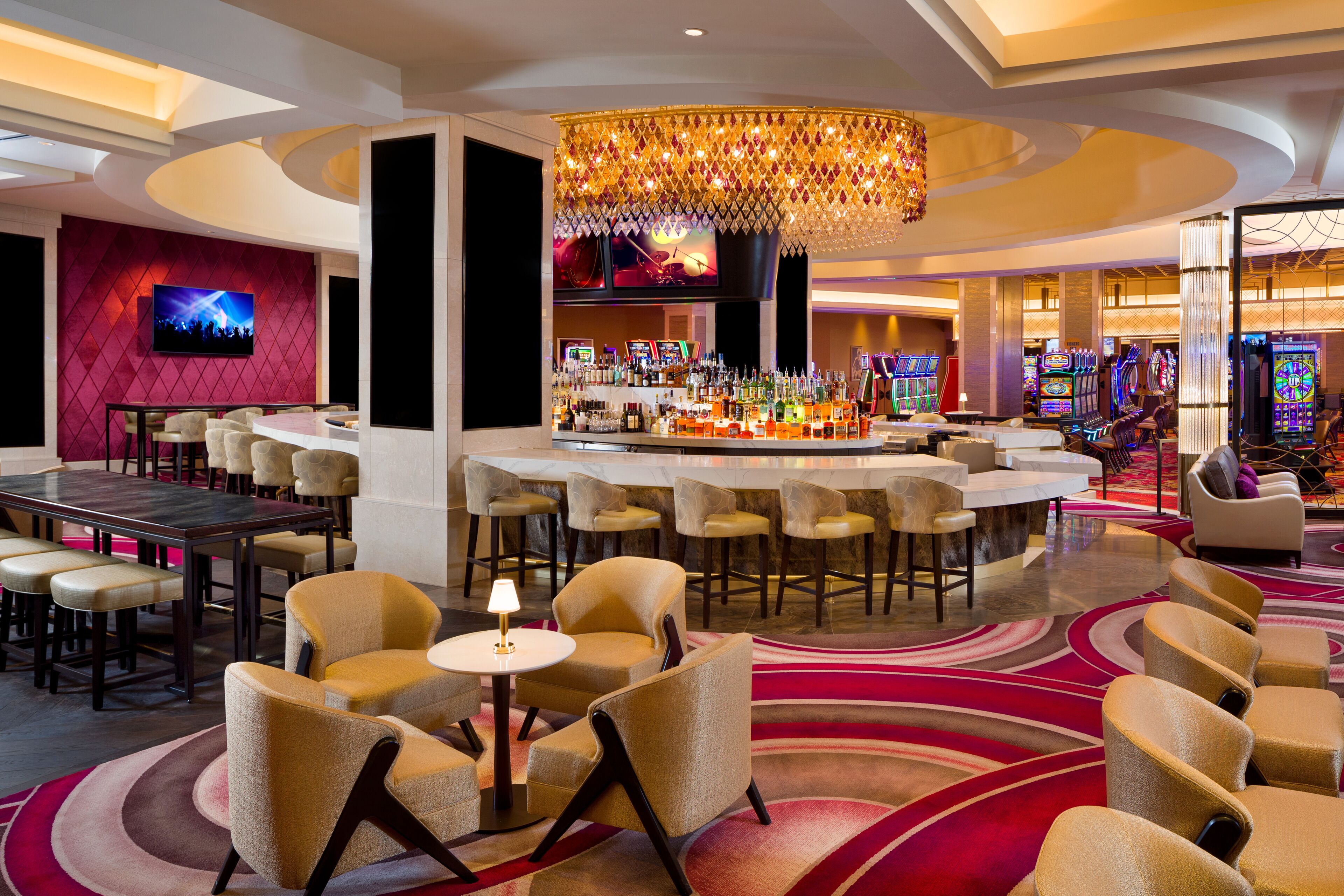 A hotel lobby with a bar area, seating arrangements, and a large screen.