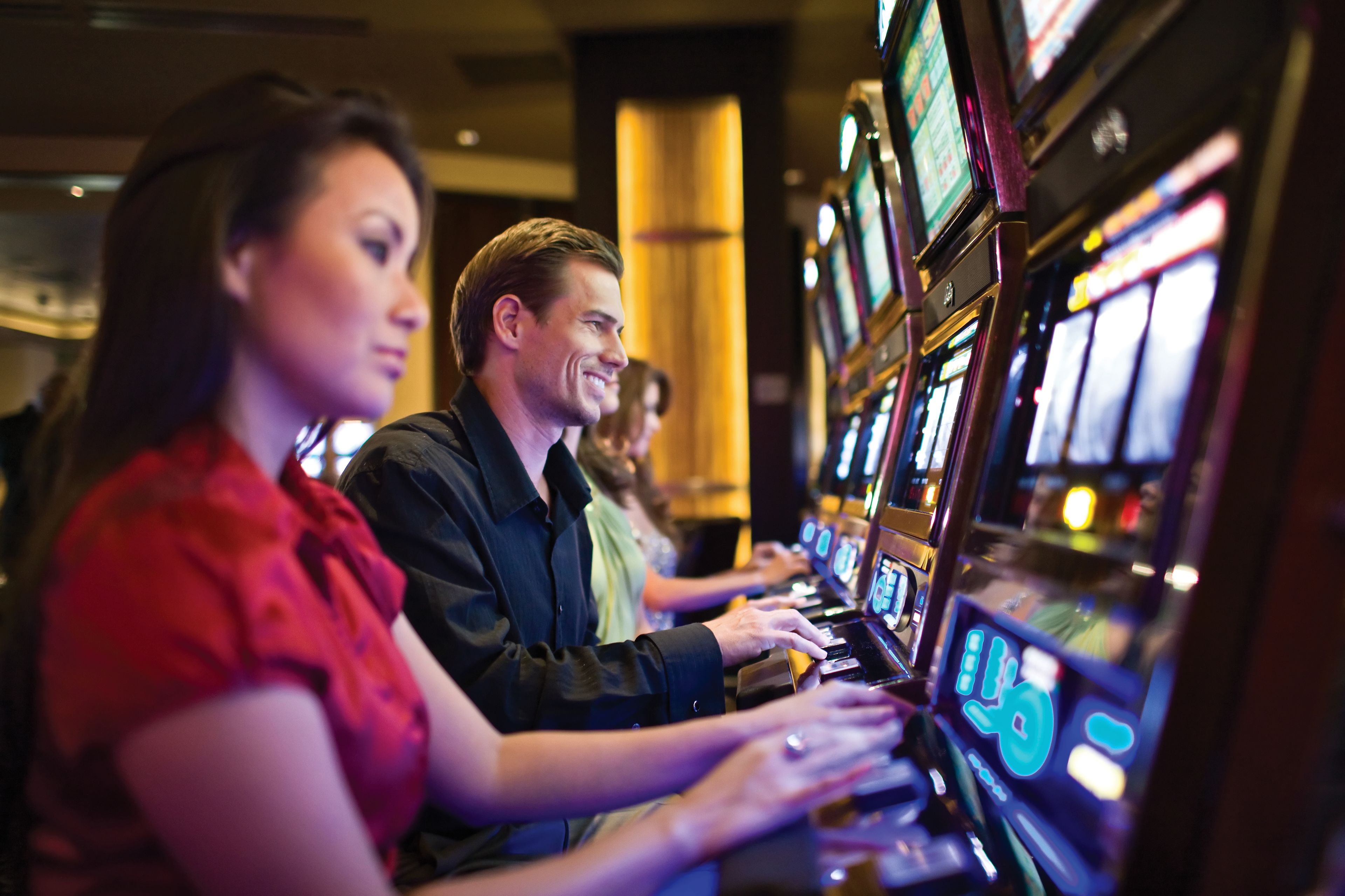 A group of people playing slot machines in a casino.
