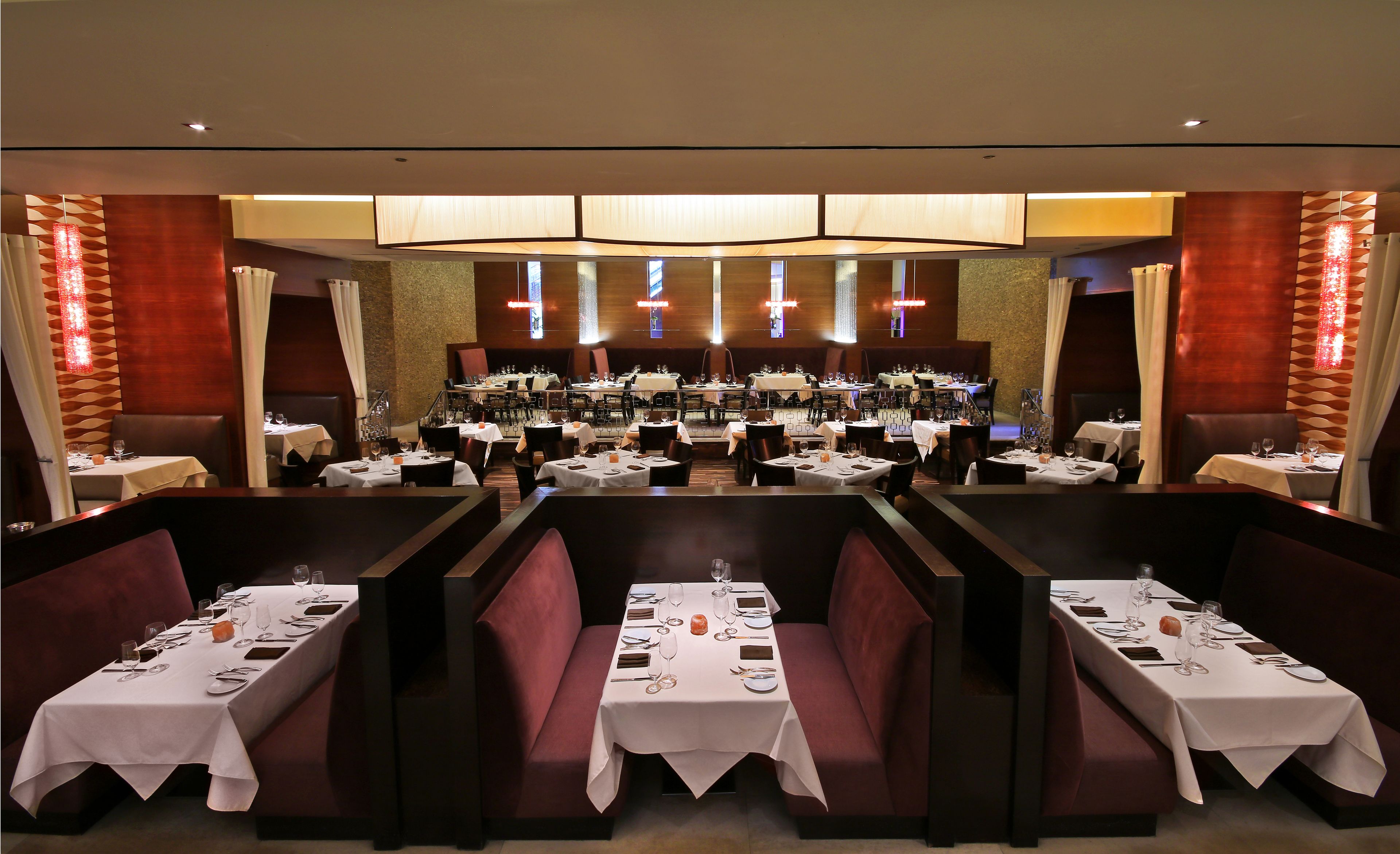 A restaurant with multiple dining tables, booths, and a central stage area.