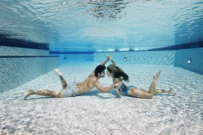 Vista subacuática de una piscina con paredes de azulejos y una superficie de agua azul cristalina.