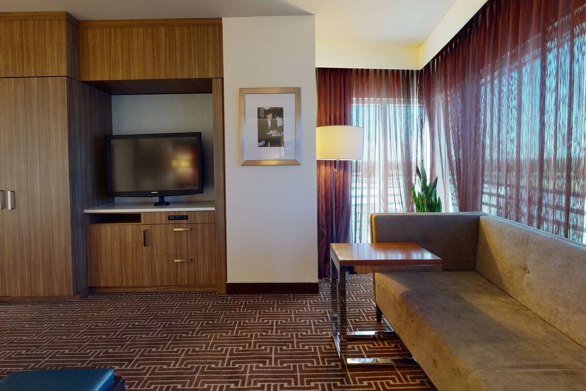 Une chambre d’hôtel équipée d’une télévision, d’un canapé et d’un bureau.