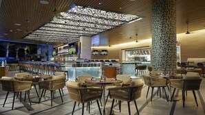 A modern bar area with a high ceiling, bar stools, and a counter with a marble top.