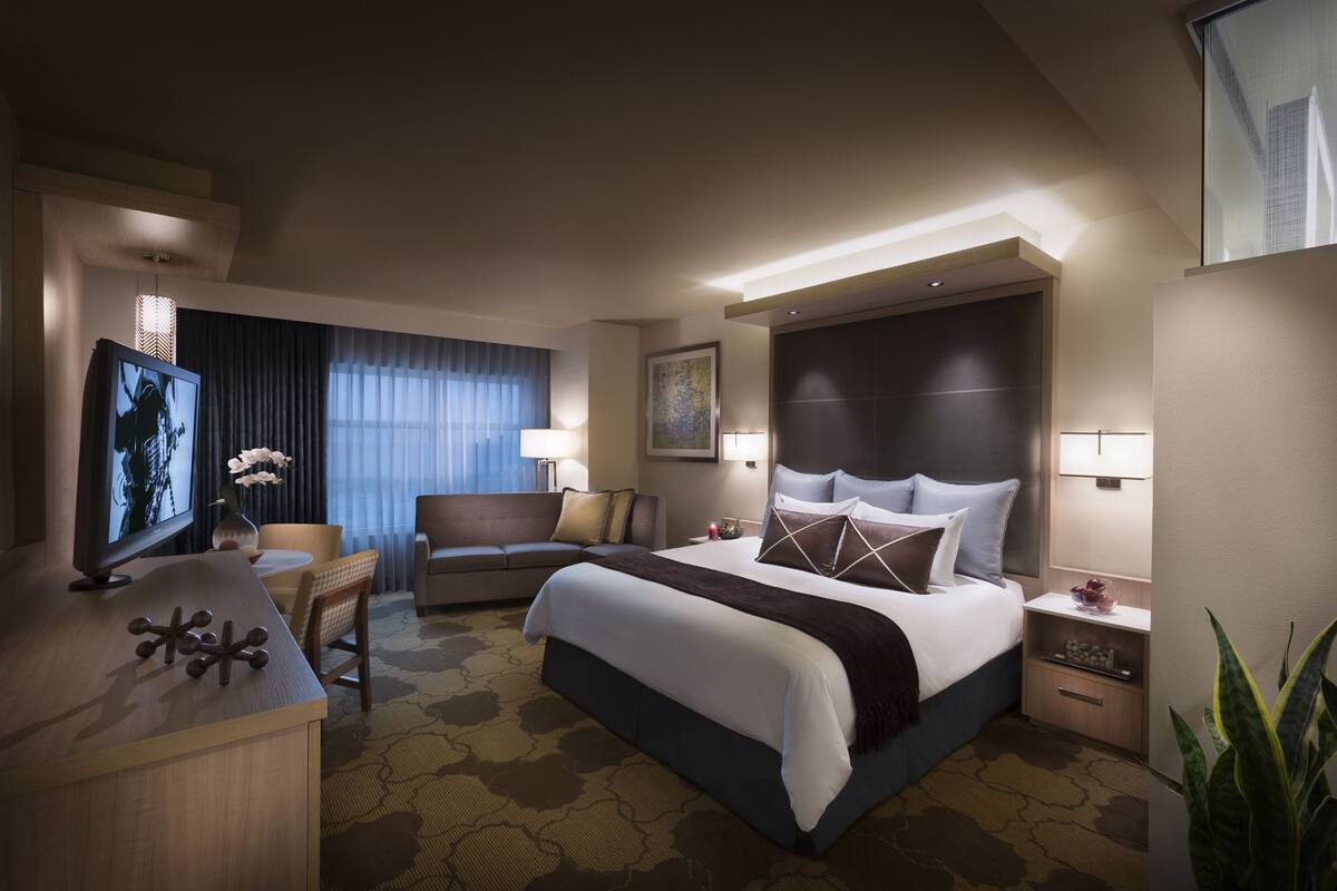 Une chambre d’hôtel moderne équipée d’un grand lit, d’un bureau, d’une télévision et d’un canapé.