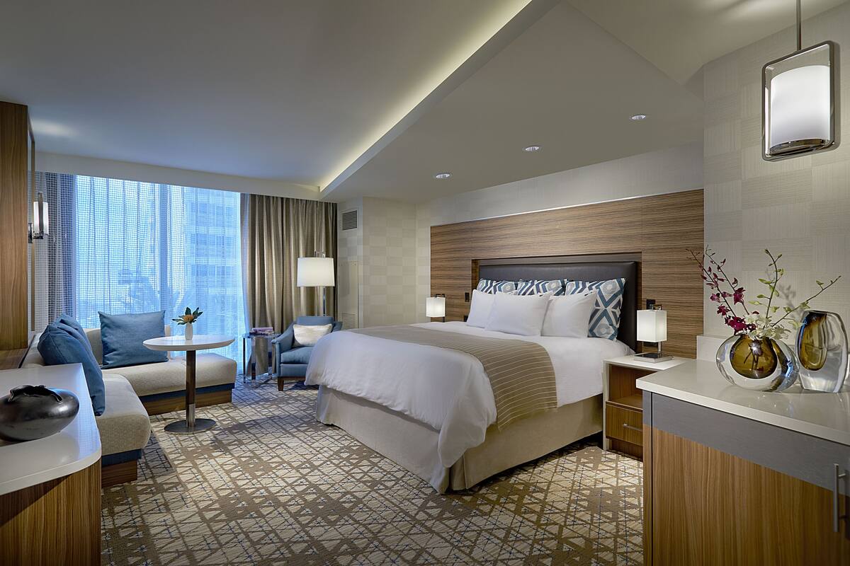 Une chambre d’hôtel avec un grand lit, un canapé, une petite table et un bureau.