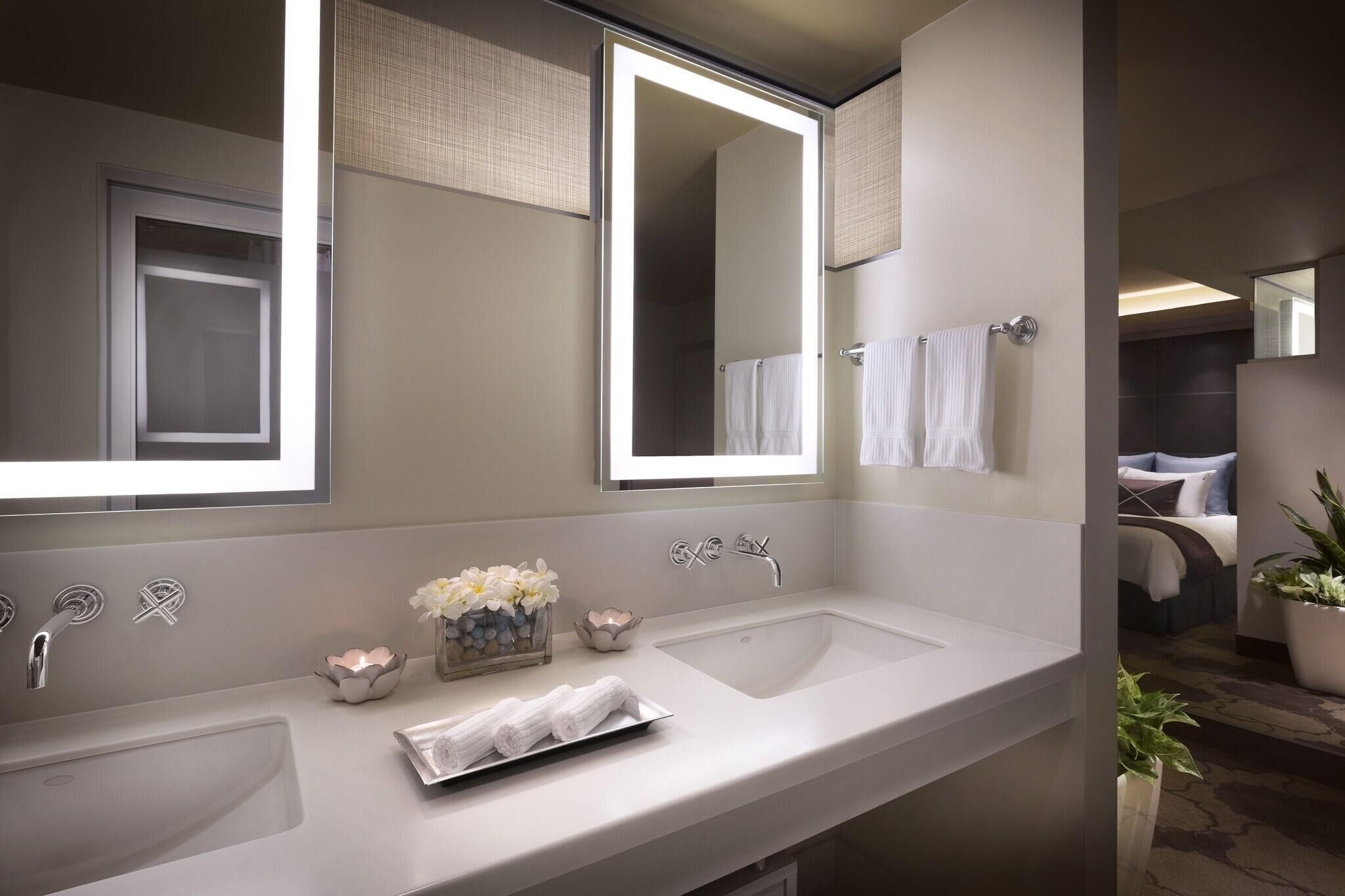 Un baño moderno con dos lavamanos, un espejo grande y un perchero para toallas.