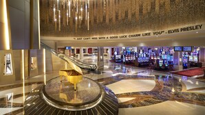 A spacious lobby with a grand piano, a large chandelier, and a quote by Elvis Presley on the wall.