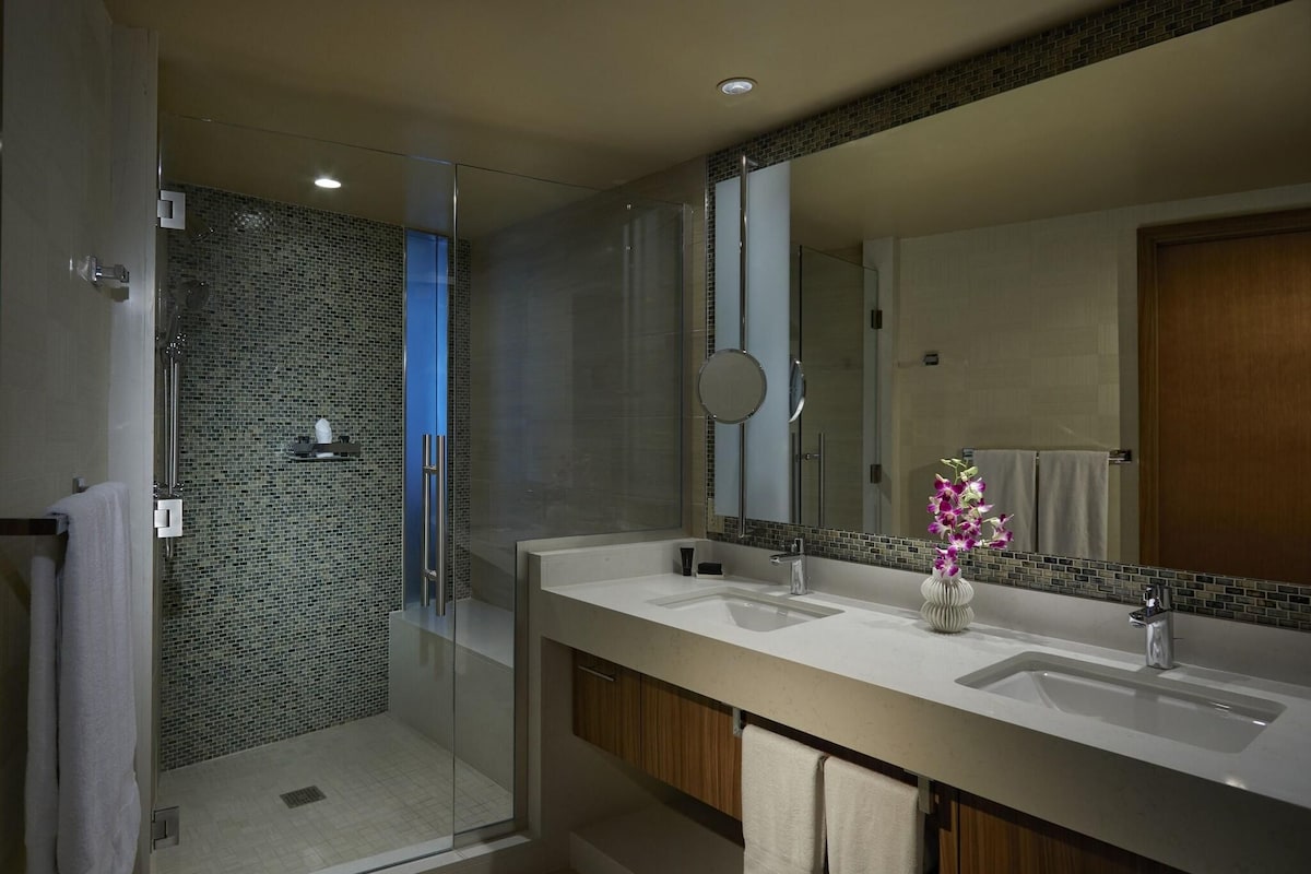 Une salle de bain moderne avec deux lavabos, un grand miroir et un espace douche doté de portes en verre.