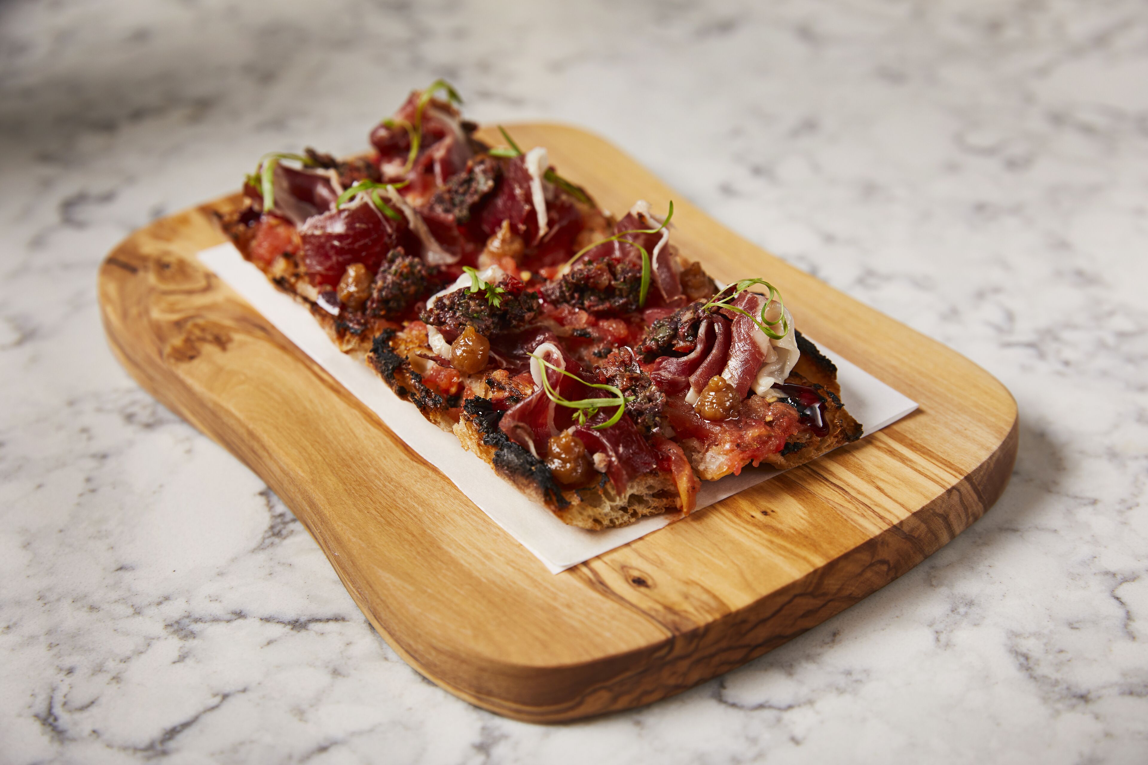 A wooden serving board with a rectangular piece of food on it.