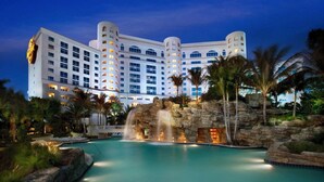 A large hotel with multiple floors, a swimming pool, and a waterfall feature.