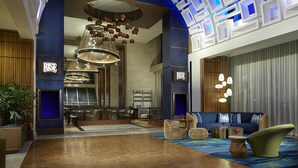 A spacious lobby with a modern chandelier, seating area, and a 'RISE' sign.