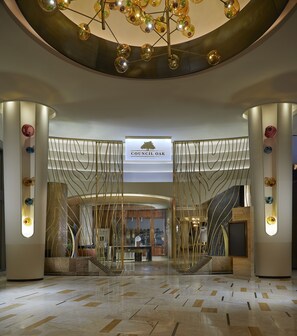A modern lobby with a central staircase, a chandelier, and a sign reading "Council Oak."