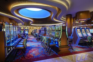 A casino with multiple slot machines, comfortable seating, and a unique ceiling design.