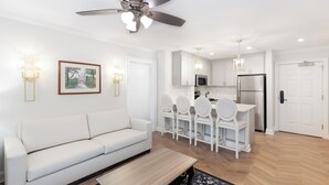 Een moderne woonkamer met een witte bank, een houten salontafel en een plafondventilator.