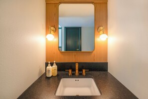 A bathroom with a white sink, wooden vanity, and two wall-mounted lights.