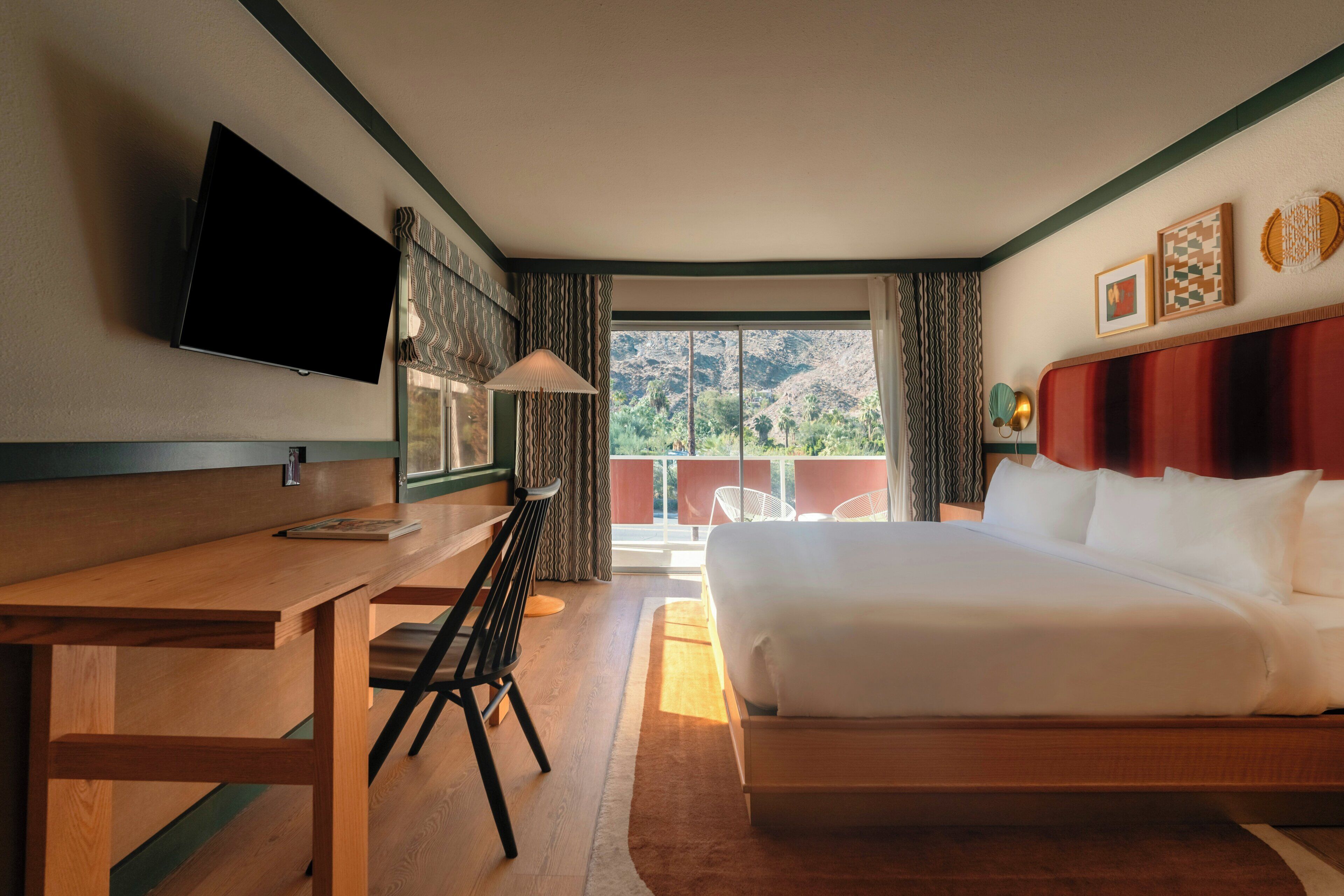 A hotel room with a bed, a desk, a television, and a view of the outdoors.