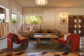 A living room with a sofa, two armchairs, a coffee table, and a large window with curtains.