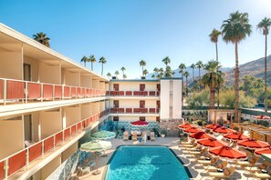 Un hôtel doté d’une piscine, de plusieurs étages, d’un espace extérieur aménagé, de palmiers et avec une vue sur les montagnes en arrière-plan.