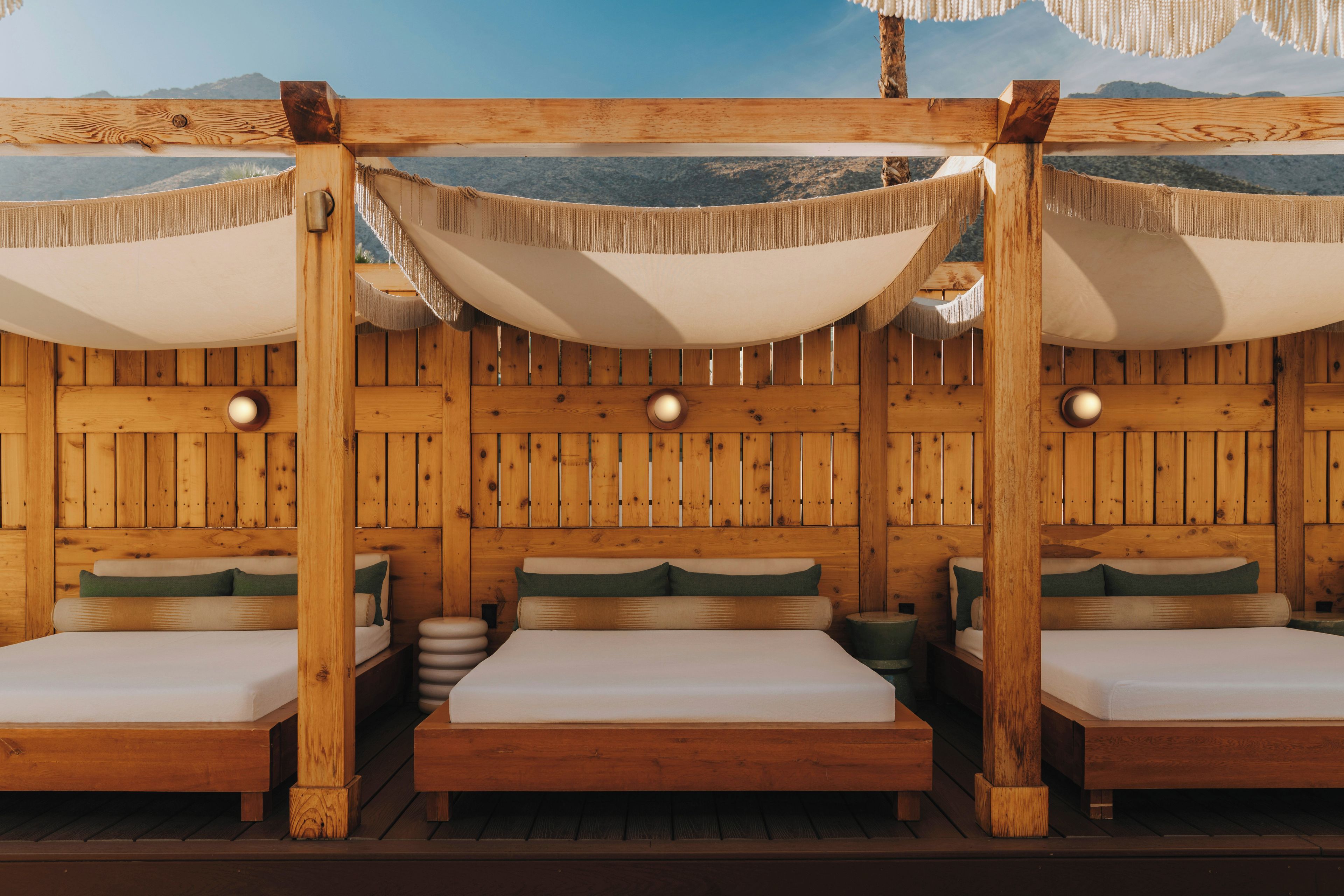 A wooden room with three beds, each with a canopy and pillows.