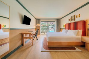 Quarto de hotel com cama, escrivaninha, cadeira, televisão e vista para o exterior.