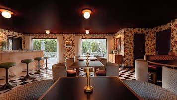 A restaurant with a checkered floor, patterned wallpaper, and a bar area.