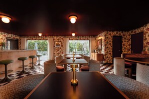 A restaurant with a checkered floor, patterned wallpaper, and a bar area.