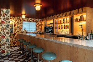 A bar area with a checkered floor, wooden bar counter, and stools.