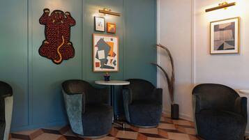 Una habitación con dos sillones, una mesita y decoración en la pared.