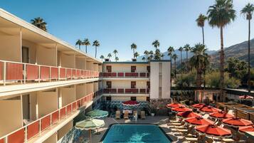 Un hotel con piscina, varios balcones y palmeras.