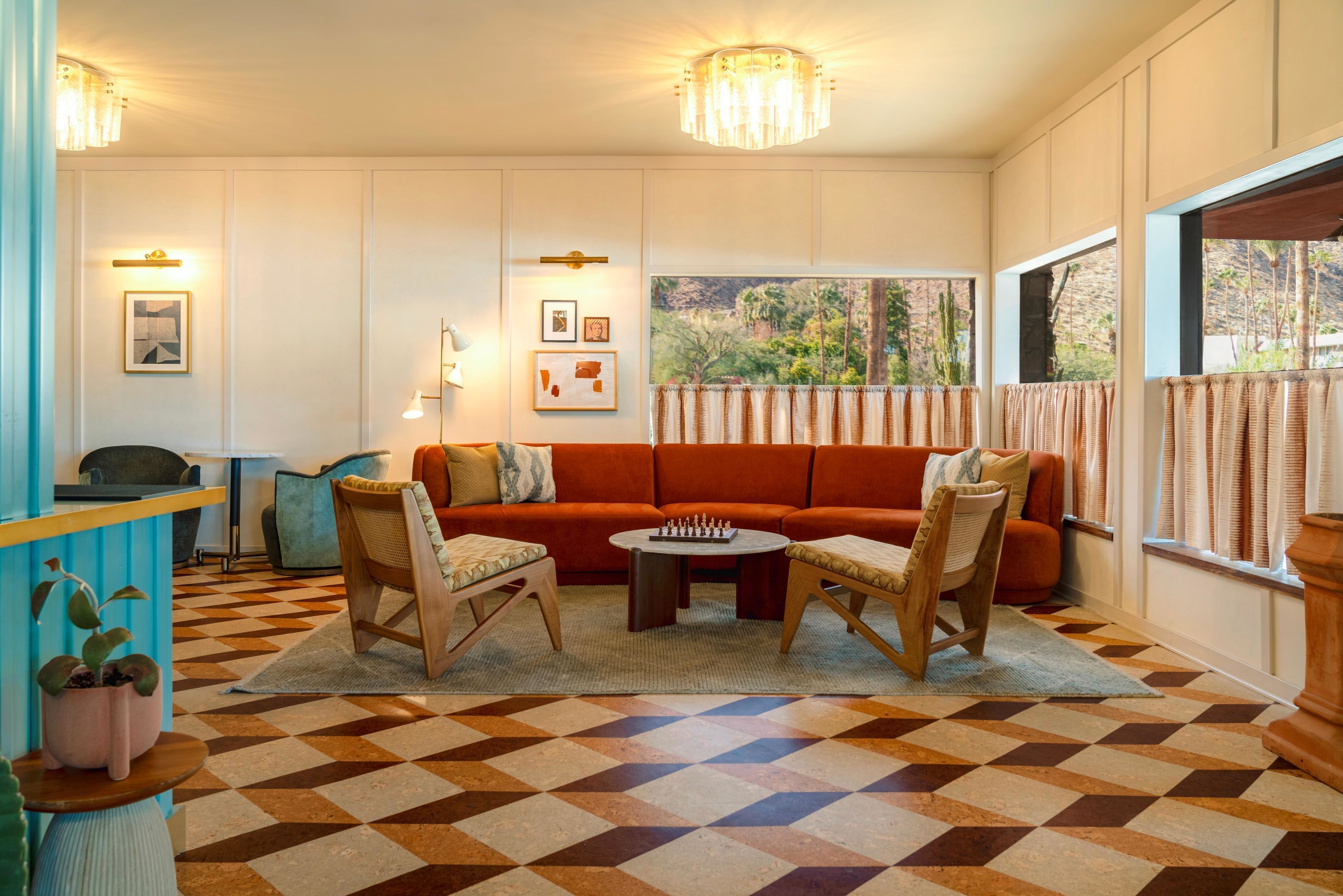Um quarto com piso xadrez, um sofá, duas cadeiras, uma mesa de centro e uma janela com cortinas.
