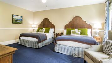 A hotel room with two beds, a wooden headboard, a painting on the wall, and a blue carpet.