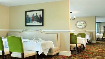 A dining area with booths and tables, a framed artwork on the wall, and a carpeted floor.