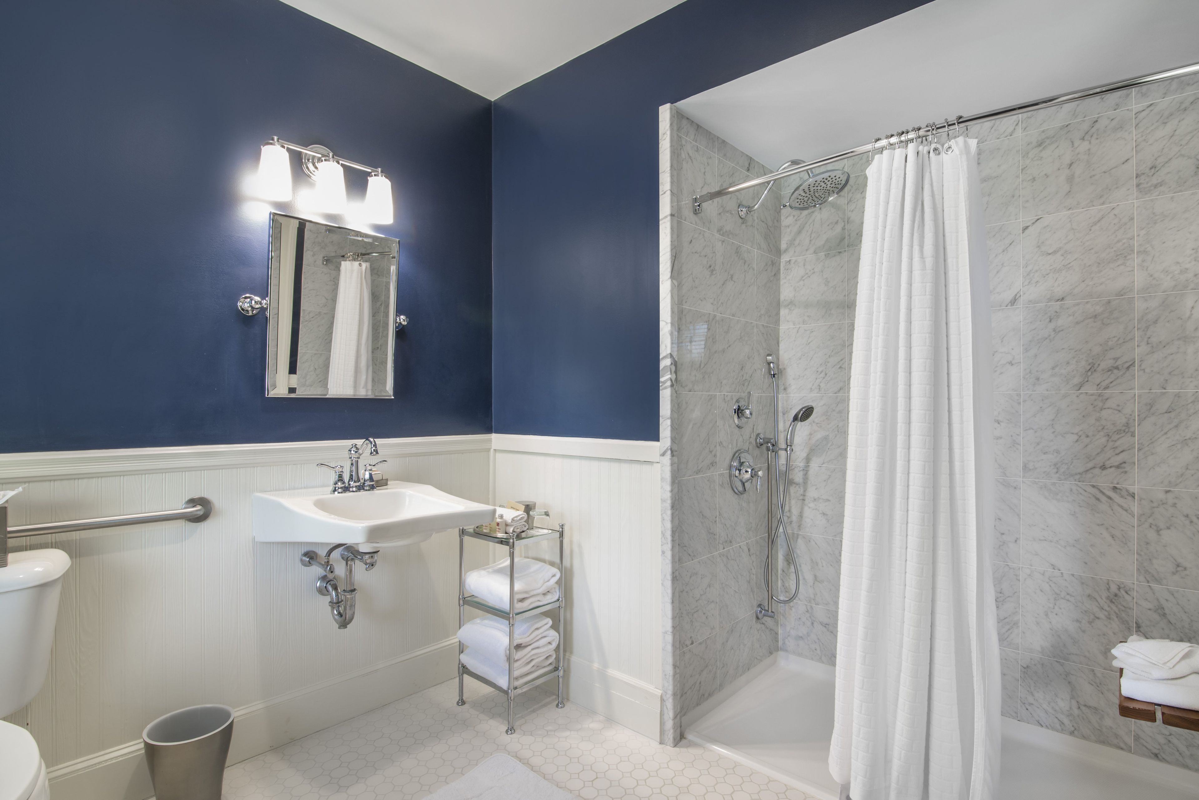 A bathroom with a glass-enclosed shower, a sink with a mirror above it, and a toilet.