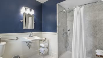 A bathroom with a glass-enclosed shower, a sink with a mirror above it, and a toilet.