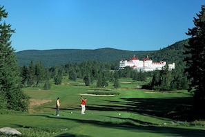 A golf course with a large building in the background. - Omni Bretton Arms Inn at Mount Washington (Bretton Woods)