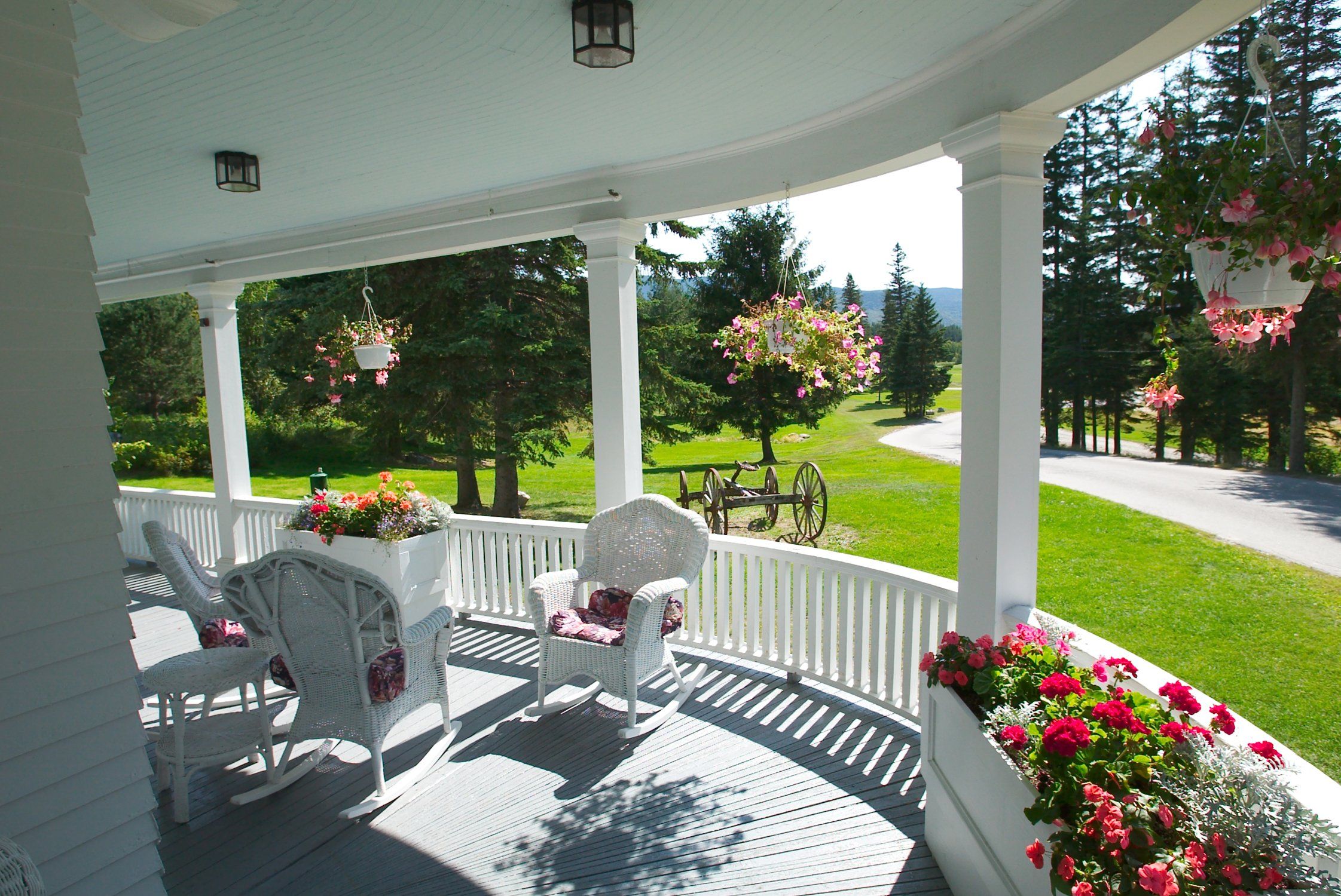 A covered porch with wicker rocking chairs and hanging flower baskets.