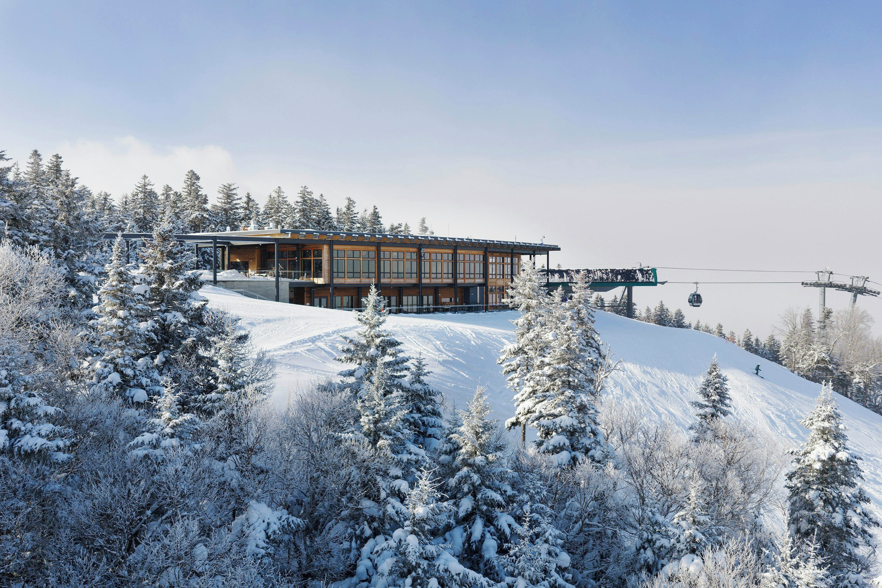 A modern building with large windows and a ski lift in the background.