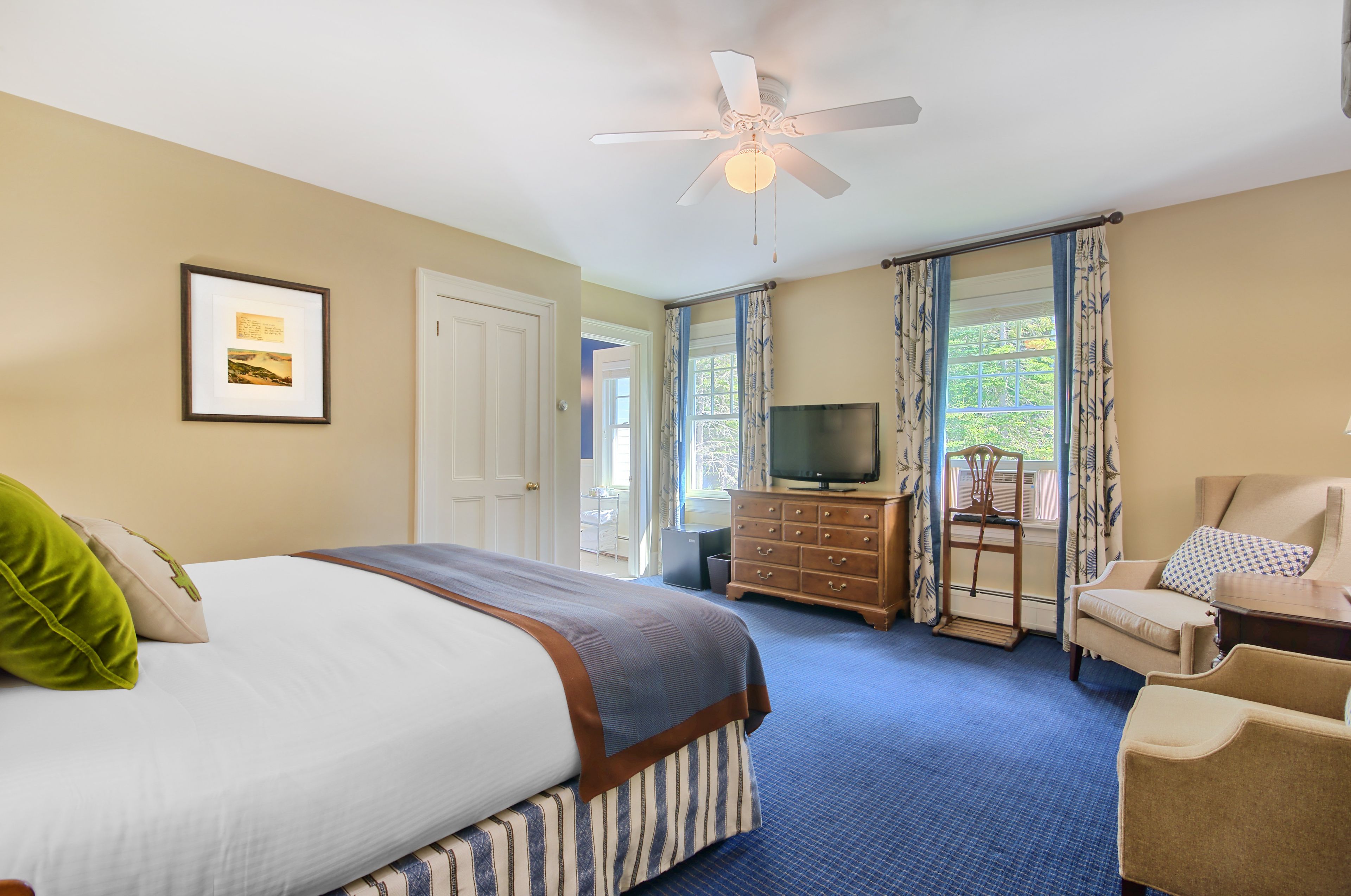 Une chambre d’hôtel équipée d’un lit, d’une télévision, d’une chaise et d’un ventilateur de plafond.