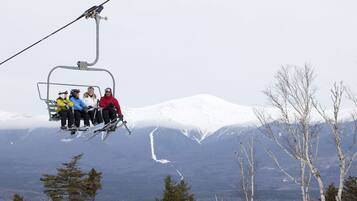 A ski lift carrying skiers with a snowy mountain landscape in the background.