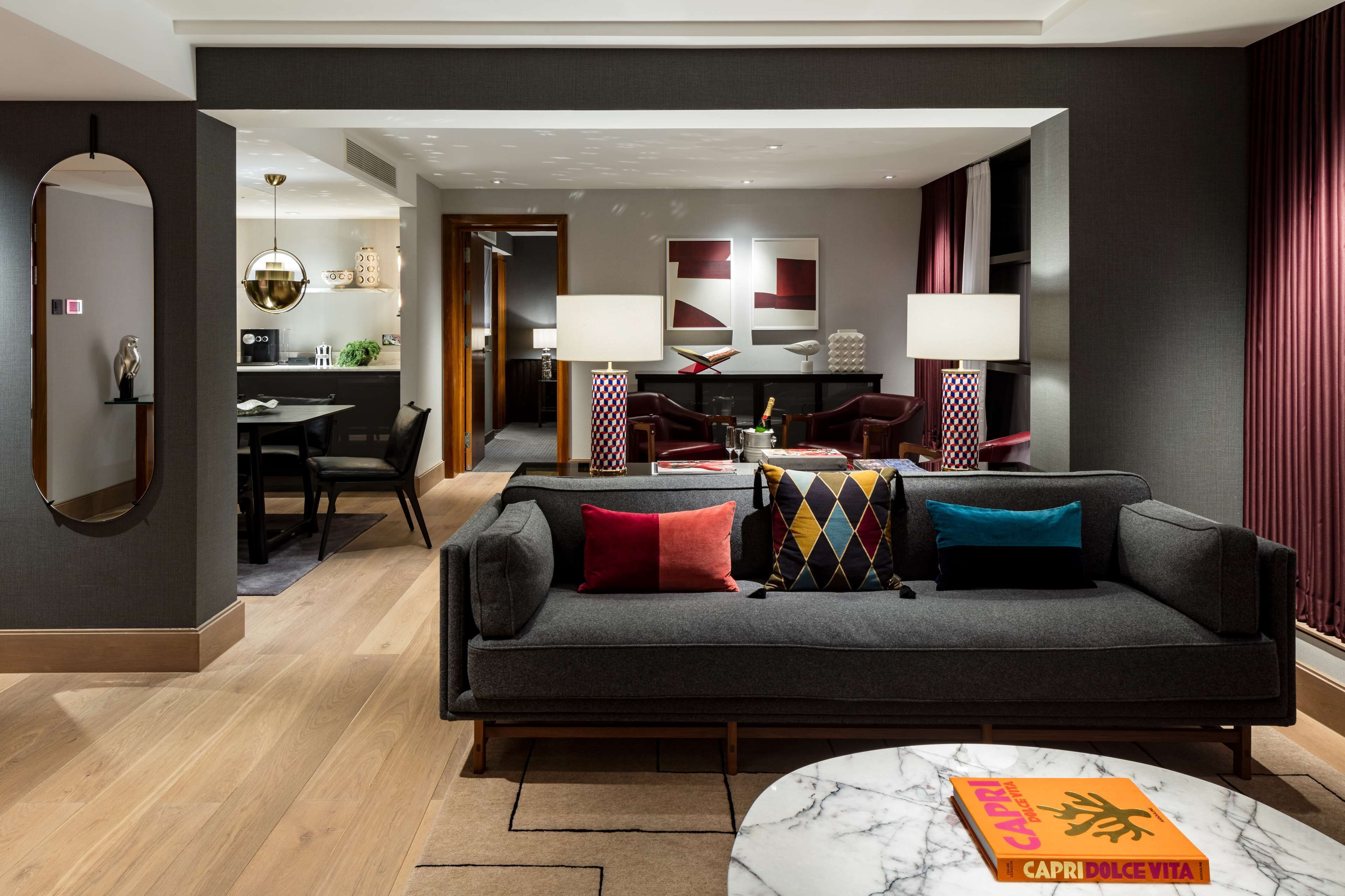 A modern living room with a grey sofa, a marble coffee table, and a dining area in the background.