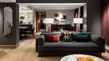 A modern living room with a grey sofa, a marble coffee table, and a dining area in the background.