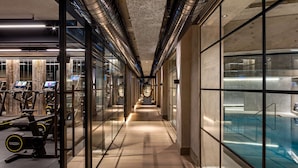 A modern gym with exercise equipment, a glass wall, and a pool area.