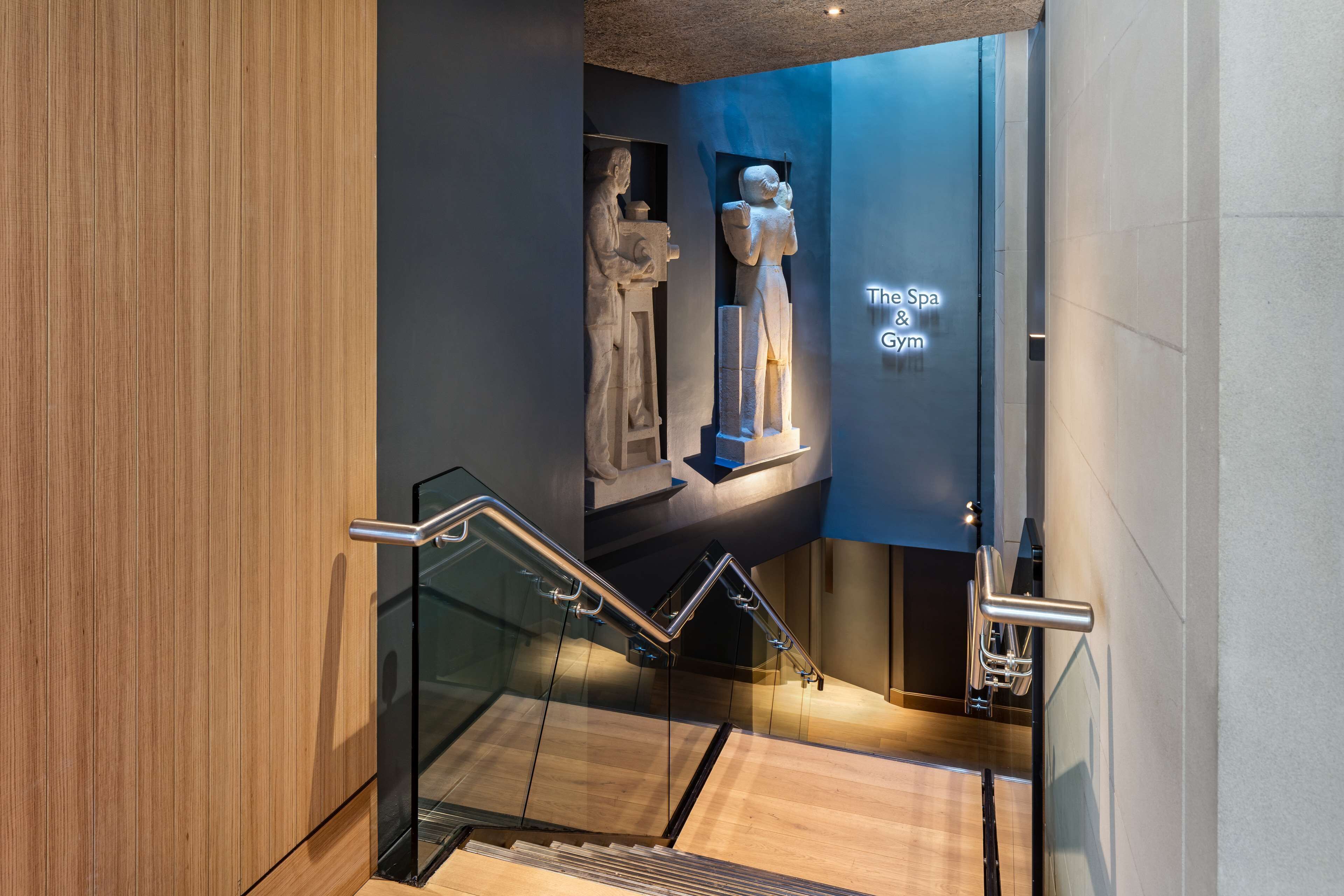 A modern interior with a staircase, glass railings, and a sign for 'The Spa & Gym'.