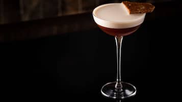 Un cóctel en una copa de martini con una tostada en el borde.