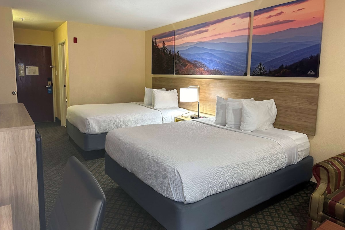 A hotel room with two beds, a desk, and a chair.