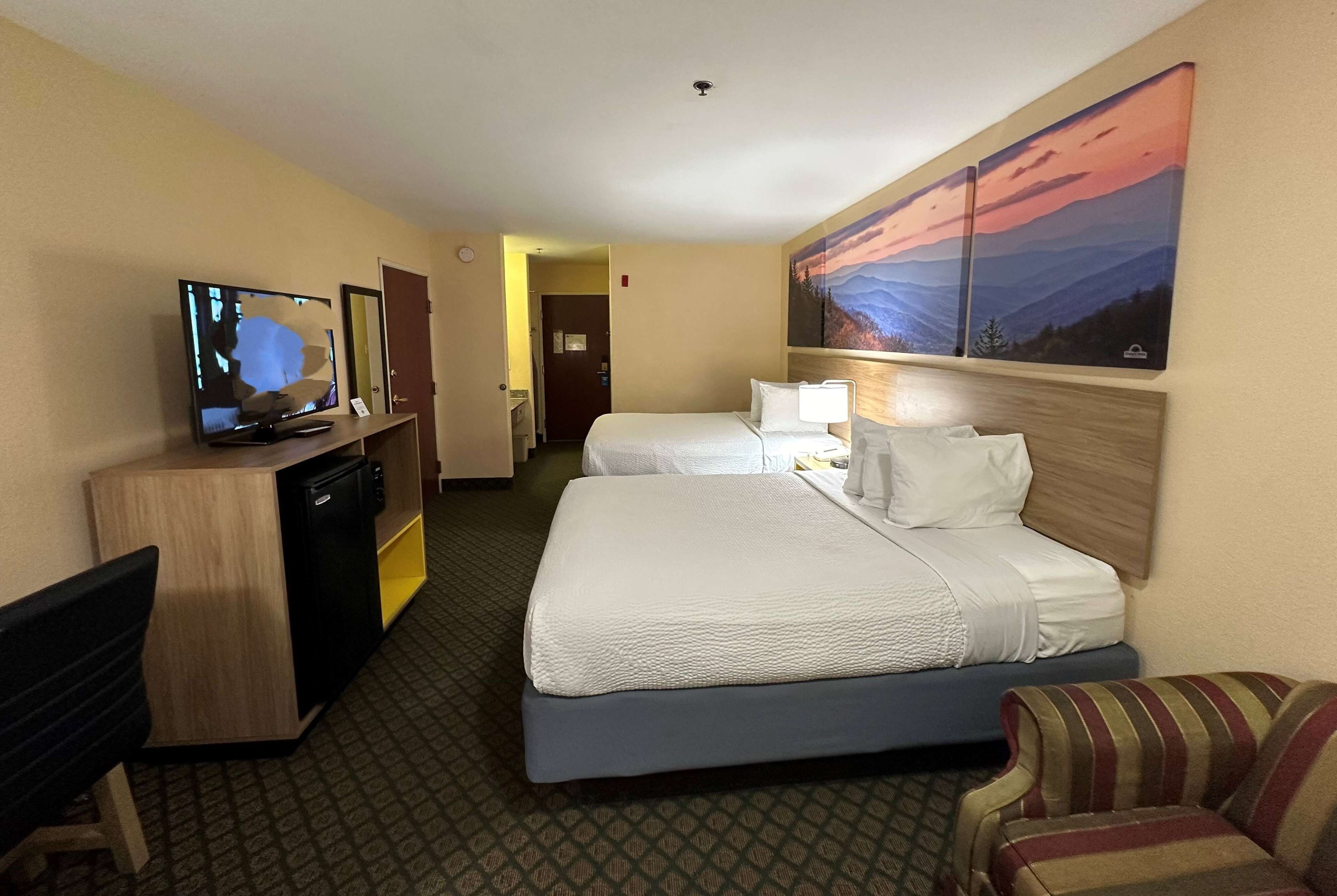 Een hotelkamer met een bed, een bureau, een televisietoestel en een schilderij aan de muur.