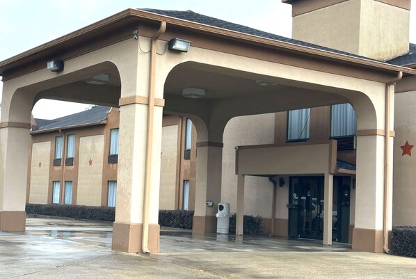 A building with a covered entrance, large windows, and a star emblem on the wall. - Days Inn & Suites by Wyndham Eunice (Eunice)