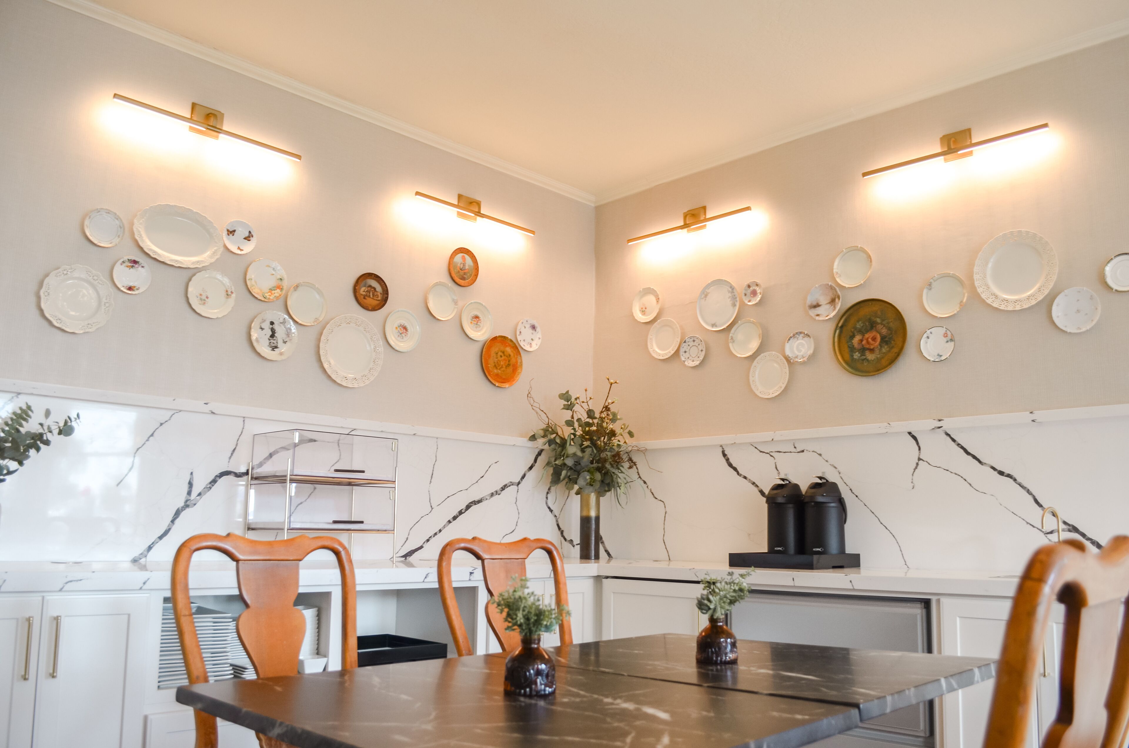 Un coin repas agrémenté d’un pare-feu en marbre, d’une table à manger noire, de chaises en bois et d’appliques murales.