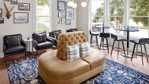 A living room with a tufted sofa, black leather chairs, a round table with two chairs, and a chandelier. - Gosby House Inn, A Four Sisters Inn (Pacific Grove)